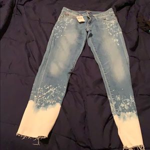 Indigo jeans with white paint splatters.